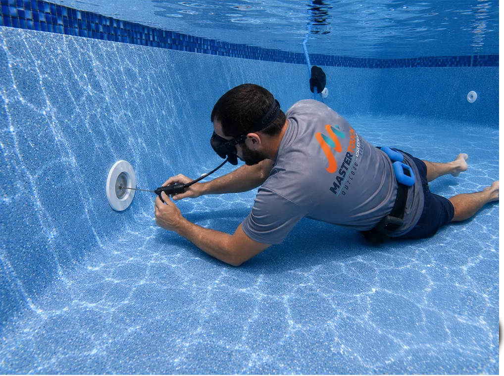Master Touch technician underwater servicing a pool light during a repair