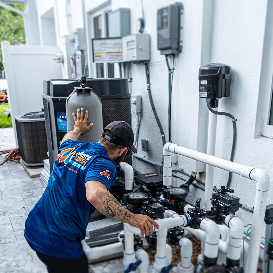 Master Touch technician servicing a pool equipment pad with heater, pumps and valves