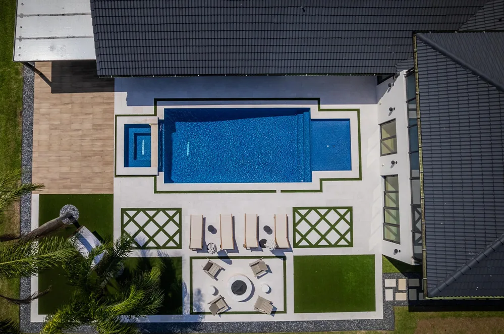 Aerial view of a pool with spa and paver patio